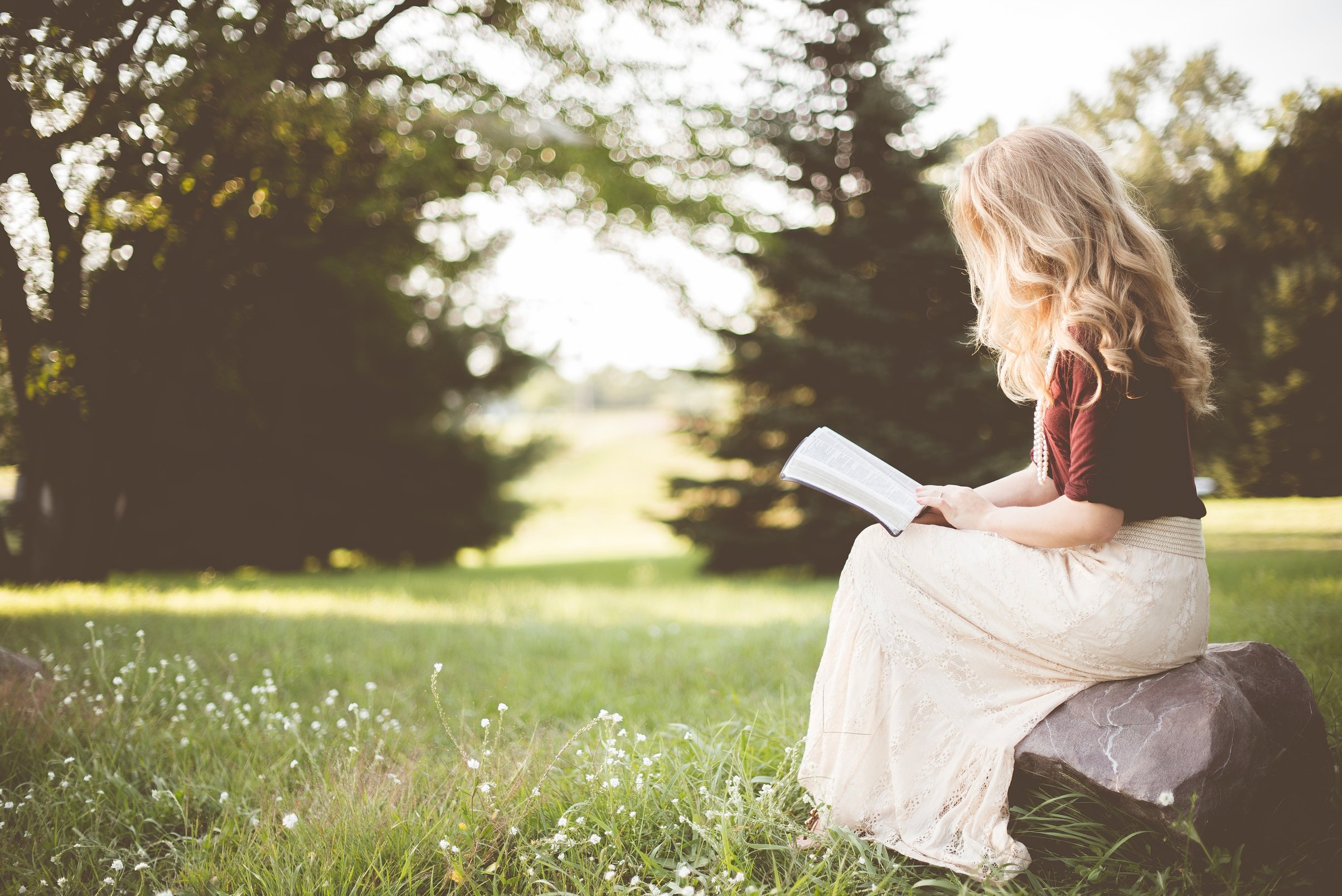 Woman Sitting and Reading in a Garden