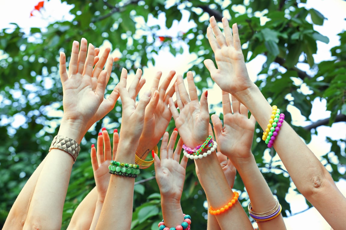 Hands Wearing Colorful Bracelets Raised Outdoors